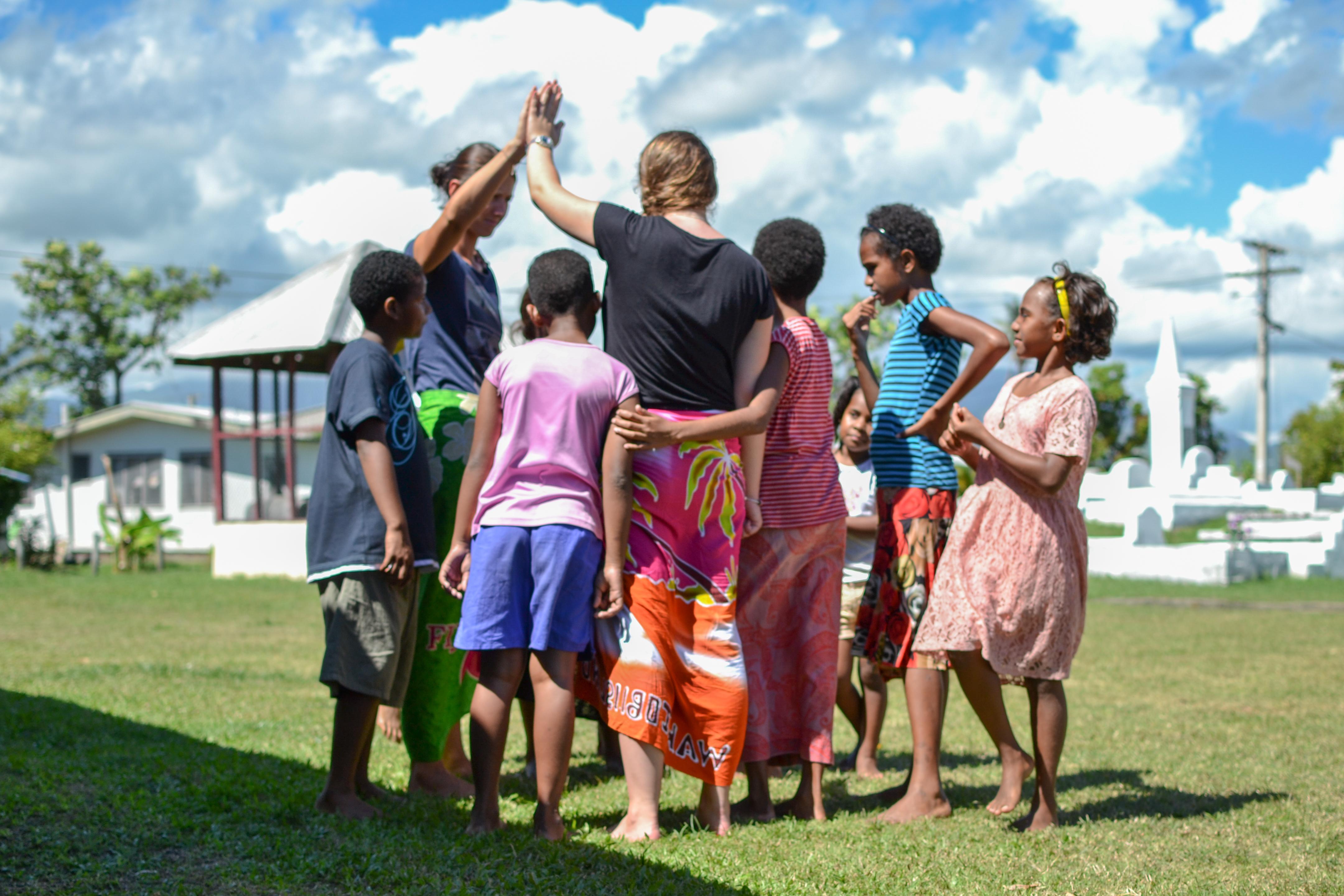 Adolescentes realizando trabajo voluntario con estudiantes en Fiyi. Jóvenes voluntarios realizando una actividad con los niños.